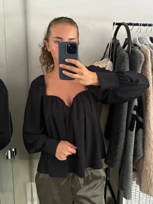 Svart offshoulder blus med vida ärmar - Trendig svart blus med offshoulder-modell och vida, långa ärmar. Passar även S