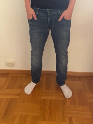 Blå slim fit jeans herr - Snygga blå slim fit jeans med klassisk femficksdesign och normal midja. Jeansen har en lätt tvättad look och smal passform som sitter tajt över benen. Perfekta för en avslappnad och trendig stil. Tillverkade i denim med stretch för extra komfort.