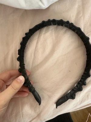 Svart diadem med paljetter - Snyggt svart diadem med glittrande paljetter över hela ytan. Diademet har en vadderad och lite bredare form som ger volym och sticker ut. Materialet är tyg täckt med små svarta paljetter som reflekterar ljuset. Perfekt accessoar för att lyfta din look.
