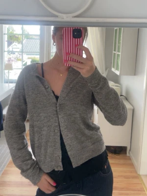 Grå kofta från InWear med guldskimrande  - Mysig grå kofta från InWear med guldskimrande i och enkel knäppning framtill. Koftan har en rak passform, långa ärmar och är stickad i ett mjukt material som passar perfekt till lager på lager. Enkel och stilren design som funkar till det mesta. Står att det är storlek L men jag på bilden har vanligtvis S eller M