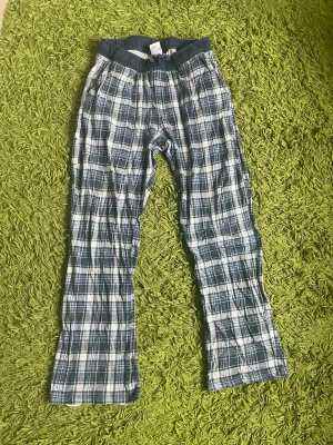 Rutiga pyjamasbyxor i bomull - Mysiga pyjamasbyxor med blåvitt rutmönster och elastisk midja. Tillverkade i mjuk bomull som känns skön mot huden. Perfekta för slappa dagar hemma eller när du vill chilla extra mycket. Finns lite små hål där nere vid fötterna men det är bara jätte små