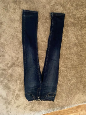Mörkblå skinny jeans med stretch - Säljer ett par mörkblå skinny jeans med lätt slitning och klassiska fem fickor. Jeansen har smal passform och är tillverkade i stretchigt denimtyg för extra komfort. Perfekta till sneakers eller boots.