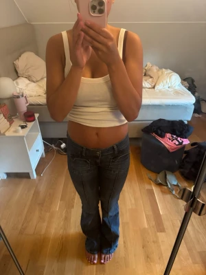 Mörkblå bootcut jeans - Säljer ett par mörkblå bootcut jeans med låg midja och klassiska fickor både fram och bak. Jeansen har kontrastsömmar och en snygg tvätt som ger en cool vintagekänsla. Perfekta till en avslappnad och trendig look.