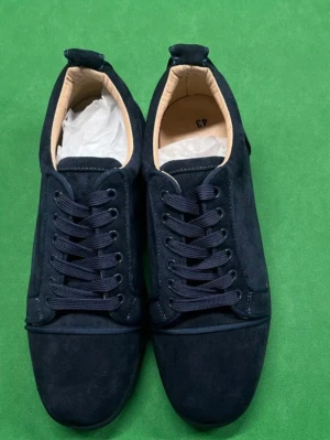 Mörkblå sneakers med röd sula - Snygga mörkblå sneakers i mocka med klassisk låg profil och kontrasterande röd sula. Skorna har svarta snören, diskreta metalldetaljer på sidan och en mjuk beige insida. Perfekta för dig som vill ha en stilren men ändå unik look.