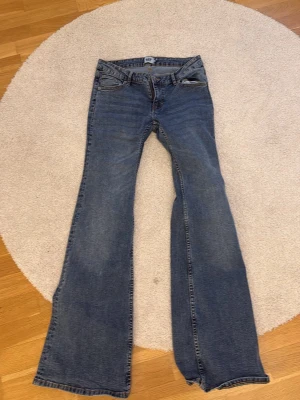 Blå bootcut jeans med låg midja - Säljer ett par klassiska blå bootcut jeans med låg midja och fem fickor. Jeansen har en lätt tvättad look och vida ben från knät och ner. Perfekta för dig som gillar retrostil och vill ha ett par jeans som sticker ut lite extra. Helt oanvänd fast utan lapp(: