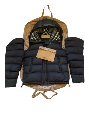 Burberry jacka & väst - Burberry dunjacka i populär modell med hög komfort och premiumkänsla. Värmande dunfyllning och stilren design som passar perfekt till höst och vinter.  Skick enligt bilder. Jackan har smutsmärken, lagning på de nedre panelerna samt en utbytt fickdragkedja, vilket är reflekterat i priset. Trots detta ger den fortfarande ett mycket bra helhetsintryck.  Storlek M. Äkta Burberry. Ett prisvärt sätt att få tag på en exklusiv designerjacka. Inga bud, fast pris