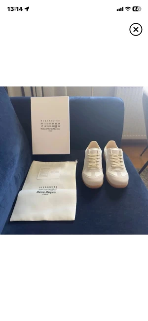 Intressekoll på vita gats - Stilrena vita sneakers från Maison Margiela med klassisk låg silhuett och beige sula. Skorna har vita snören och är tillverkade i slätt läder med diskreta detaljer. Perfekta för dig som gillar minimalistisk och clean stil.