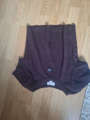 Brun ribbad t-shirt Calvin Klein - Snygg brun t-shirt från Calvin Klein Jeans med ribbad struktur och diskret CK-logga på bröstet. Klassisk passform och korta ärmar, perfekt till jeans eller kjol för en clean look.