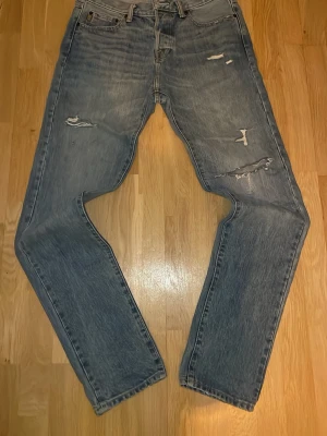 Ljusblå slitna jeans Abercrombie - Säljer ett par ljusblå jeans från Abercrombie & Fitch med slitningar och hål på benen för en trendig, avslappnad look. Klassisk femficksmodell med slim passform och snygga detaljer i sömmarna. Perfekta för dig som gillar streetstyle. Pris kan självklart diskuteras. Hör av er vid frågor! 😃32/34
