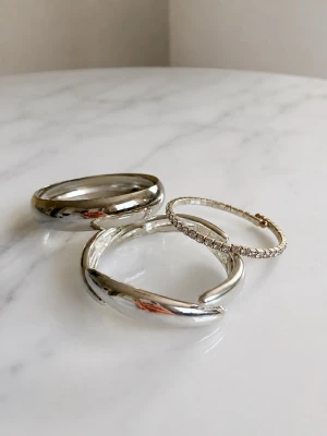🤍 Silverarmband – 3-pack | OANVÄNDA - Säljer tre superfina helt oanvända silverfärgade armband 🤍 Endast testade för bilderna, annars aldrig använda.  ✨ Alla tre är oanvända ✨ Två chunky statement-armband ✨ Ett tunnare strassarmband med glittrande stenar ✨ Ett av armbanden är från Gemini Jewellery – lappen sitter fortfarande kvar ✨ Jättefina att bära tillsammans eller var för sig   Superfint set som passar både till vardags och fest 🩶