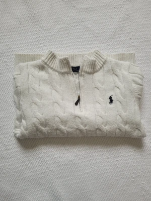 Vit kabelstickad tröja Polo Ralph Lauren - Kabelstickad vit quarterzip tröja från Polo Ralph Lauren! Är lite för liten för mig (Storlek M). Inga defekter, gott skick, skickar nytvättad med påse och lappar samma dag eller senast nästa. (Om den skulle råka vara i tvätten blir det en dag senare). Tar helst bara bud för snabba köp :)