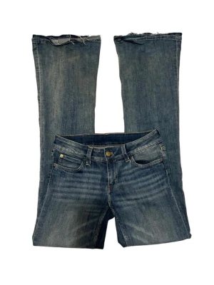Blå bootcut jeans med rå kant - Säljer ett par blå bootcut jeans med rå, avklippt kant nedtill. Jeansen har klassisk femficksdesign, knappgylf och en snygg tvätt med lätt slitning. Perfekta för dig som gillar en avslappnad och trendig stil.