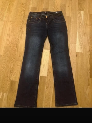 Mörkblå bootcut jeans från LTB - Snygga mörkblå bootcut jeans från LTB med klassisk femficksmodell och kontrastsömmar. Jeansen har en lätt tvättad look och gylf med knapp och dragkedja. Perfekta för dig som gillar en tidlös och avslappnad stil.