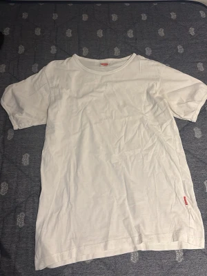 Vit t-shirt från Newbody - Klassisk vit t-shirt från Newbody i storlek L. T-shirten har rund halsringning och korta ärmar. Tillverkad i mjuk bomull som känns skön mot huden. Perfekt basplagg till garderoben.