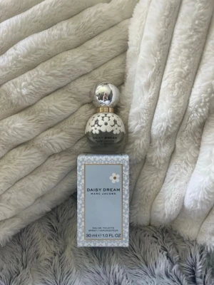 Daisy Dream parfym 30 ml - Säljer en Daisy Dream Eau de Toilette från Marc Jacobs, mängd = (se bild 2) Flaskan är rund och dekorerad med vita blommor och har en silverfärgad kork. Perfekt för dig som gillar fräscha och blommiga dofter.