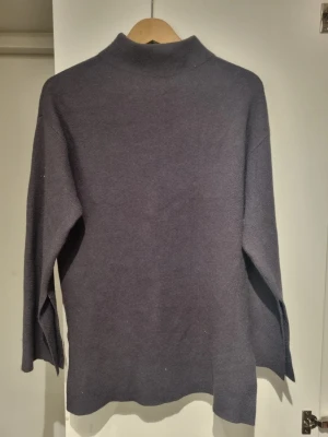 Lila stickad tröja från Bianca x Nelly - Mysig lila stickad tröja från Bianca x Nelly.com med hög hals och långa ärmar. Tröjan har en rak passform och är perfekt för kyliga dagar. Enkel och stilren design som passar till många outfits.