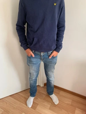 Nudie Jeans - Säljer ett par blå slim fit jeans. Jeansen har klassisk femficksdesign och normal midja. Storlek W30/L32.  Perfekta till en avslappnad stil. Endast använda en handfull gånger, så nästan nyskick.