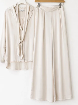 Nya oanvända Beige satinset med skjorta och byxor - Snyggt tvådelat set i beige satin med långärmad skjorta och vida byxor. Skjortan har knytband framtill och avslappnad passform, medan byxorna är höga i midjan och har breda ben. Perfekt för en chic och bekväm look. Bälte finns. 