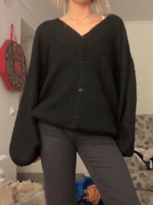 Oversized svart kofta från Nelly!! - Mysig oversized svart kofta med v-ringning och stora knappar framtill. Från Nelly och är i storlek s/M. Aldrig använd !