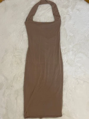Beige klänning med halterneck - En beige halterneck klänning från Madeben, storlek XS/S.