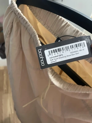 Beige långkjol med dragsko från Boohoo - . Säljer en beige långkjol från Boohoo med mjukt material och dragsko i midjan. Kjolen har en enkel och avslappnad look, perfekt för dig som gillar stilrena plagg. Aldrig hunnit använda den men  Passar till många olika outfits och är superbekväm att bära.