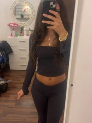 Mörkgrått set  - Säljer ett mörkgrått loungewear set med långärmad, åtsittande topp med fyrkantig ringning och matchande byxor med låg midja. Setet är i mjukt och stretchigt material, perfekt för chill dagar hemma.