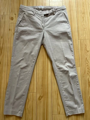 Beige chinos från Dondup - Snygga beige chinos från Dondup, tillverkade i Italien. Klassisk rak passform med snedställda fickor fram och bälteshällor i midjan. Materialet är mjukt och skönt, perfekt för en clean och stilren look.