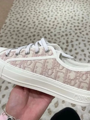 Rosa och vita Dior sneakers - Snygga sneakers från Christian Dior i beige och vitt med ikoniskt Dior-mönster i tyg. Skorna har vita snören, metallöglor och detaljer med logotypen på snörningen. Tjock vit sula och låg modell som passar till många stilar.