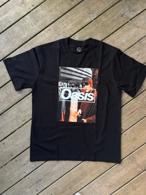 Oasis svart tshirt merch britpop vintage 90s - Svart oasis tshirt i storlek s. 100% bomull bra kvalitet. Unisex. Längd ca 69cm axelbredd ca 47,5cm. Ny. Skickar gärna i bundle.
