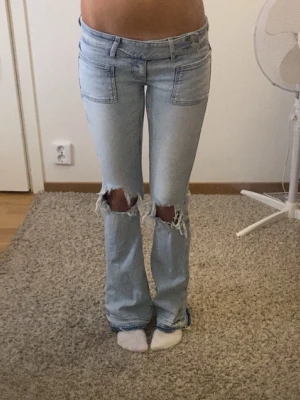 Lågmidjade bootcut jeans - Snygga ljusblå bootcut jeans med hål och lågmidja. 