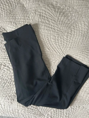 Svarta capri leggings med slits Gina Tricot - Säljer ett par svarta capri leggings med liten slits från Gina Tricot vid benslutet. De har hög midja och är tillverkade i ett stretchigt material som sitter tajt och bekvämt. Perfekta till en oversized tröja eller hoodie för en chill look. Tagen är klippt men är i storlek M