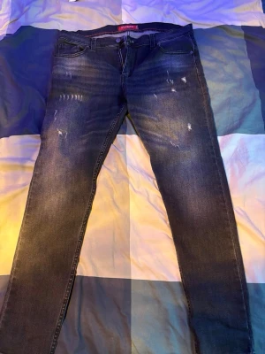 Svart/grå jeans från dsquared2 - Snygga mörkblå skinny jeans med slitna detaljer och lätt tvättad look. Jeansen har klassisk femficksdesign och smal passform som sitter tajt längs benen. Perfekta för en trendig och avslappnad stil.