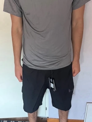 Bilder på det jag har ute (kolla nästa bild) - Säljer två par sportiga shorts, ett par svarta från Under Armour och ett par ljusgröna från Nike. Båda har en loose passform och är tillverkade i lätt polyester, perfekta för träning eller varma dagar. Klassisk design med logga på benet.