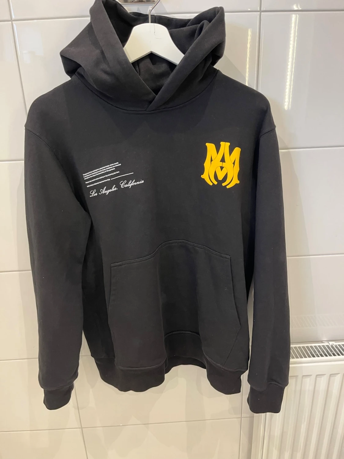 Svart hoodie med gul AMIRI-tryck