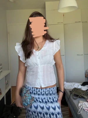 Vit blus med volangärmar och knappar - Säljer en söt vit t-shirt med volanger från Gina. Storlek 170, passar storlek XS–S. Öglan till den nedersta knappen är trasig (lätt att laga). I övrigt i utmärkt skick. 🤍