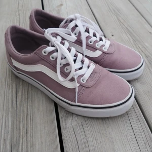 Ljuslila Vans sneakers med vit sula - Säljer ett par snygga Vans sneakers i ljuslila canvas med klassisk vit sula och vit sidostripes. Skorna har vita skosnören och låg profil, perfekta för en chill och stilren look. Passar till jeans eller shorts för en avslappnad vibe. Endast använda 1 gång så dom är i nyskick 
