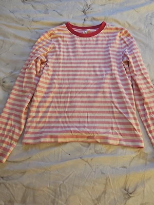 Randig långärmad topp & Other Stories - Säljer en långärmad topp från & Other Stories med rosa och vita horisontella ränder. Rund halsringning med kontrasterande röd kant. Tillverkad i mjukt bomullsmaterial. Perfekt för en avslappnad och trendig look.