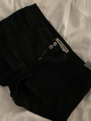 Svarta jeansshorts från Tally Weijl - Snygga svarta jeansshorts från Tally Weijl med låg midja . Shortsen har dragkedja och dubbla knappar framtill. Perfekta för varma dagar och enkla att matcha med olika toppar.storlek 34