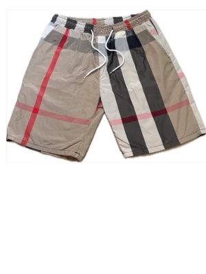 Beige rutiga shorts med snörning - Snygga beige shorts med klassiskt rutigt mönster i svart, vitt och rött. Shortsen har elastisk midja med vit snörning och är tillverkade i ett lätt material som passar perfekt till sommaren. Står 2xl men passar M!