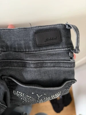 Grå jeans med nitar från Subdued - Snygga grå jeans från Subdued med raka ben och dekorativa nitar på fickan. Jeansen har klassisk femficksmodell och bälteshällor. Perfekta för dig som vill ha en cool och trendig look.