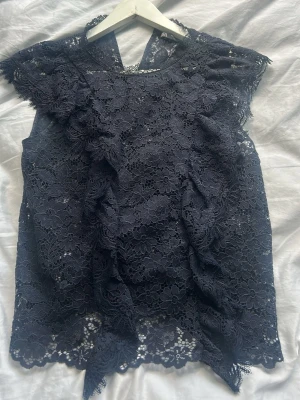Mörkblå spetsblus med volang - Säljer en mörkblå blus i spets med blommigt mönster och volangdetaljer, från zara. Använd fåtal gånger och är i bra skick🥰