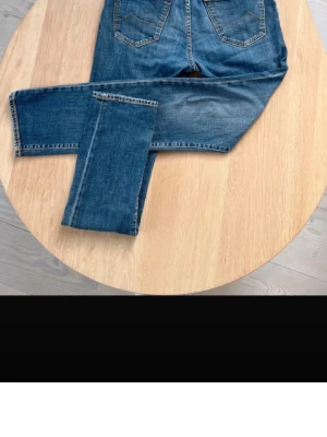 Blå raka jeans med broderi - Säljer ett par klassiska blå jeans med raka ben och snygga bakfickor från jacob cohen i den omtyckta modellen 688. På insidan finns ett broderat citat: 'Go to bed with a dream, wake up with a purpose'. Jeansen har knappgylf och rödvitrandigt innerfoder.