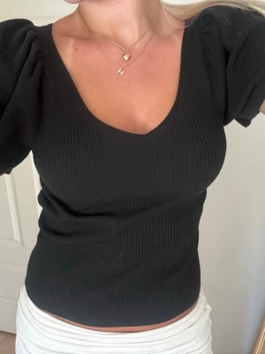 Svart ribbad topp med puffärm - Säljer en svart ribbad topp med puffiga korta ärmar och v-ringning. Storlek S💞