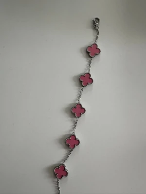 Silverarmband med rosa fyrklöver - Snyggt armband i silverfärg med fem rosa fyrklöverformade hängen. Varje hänge har en pärlad kant som ger extra detalj och stil. Perfekt accessoar för dig som vill ha något färgglatt och unikt till din look.