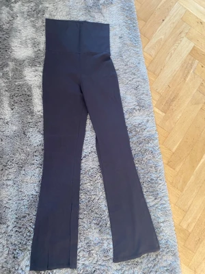 Svarta bootcut leggings med hög midja - Säljer ett par svarta leggings med hög midja och bootcut-ben. De är stretchiga och mjuka, perfekta för en avslappnad och trendig look. Materialet känns som bomullsmix med lite elastan för extra komfort.
