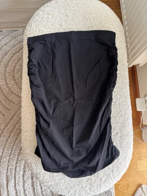 Svart kjol från Lindex - En svart kjol från Lindex i mjukt och stretchigt material. Kjolen har en enkel design med rynkade sidor som ger en snygg detalj. Perfekt att styla med en crop top eller oversized tröja för en chill look.