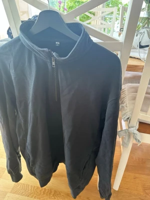 Svart halfzip hoodie från Uniqlo - Säljer en svart hoodie från Uniqlo i storlek L. Hoodien har en halv dragkedja framtill, hög krage och två fickor på sidorna. Skriv vid funderingar!
