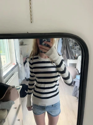 Randig svartvit tröja - Säljer en långärmad tröja med svarta och vita horisontella ränder. Tröjan har rund halsringning och ribbade muddar vid ärmslut och nederkant. Perfekt för en avslappnad och stilren look.