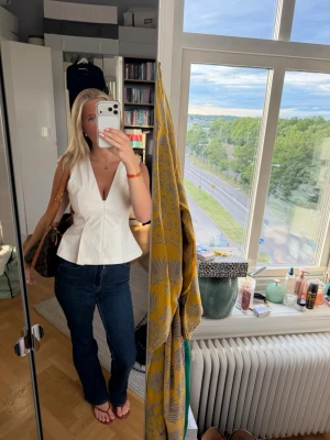 Vit v-ringad topp - Säljer en snygg vit topp med v-ringning och peplumskärning. Toppen är ärmlös och har en figurnära passform upptill som släpper ut nedtill. Perfekt att styla med jeans eller kjol 😍💕