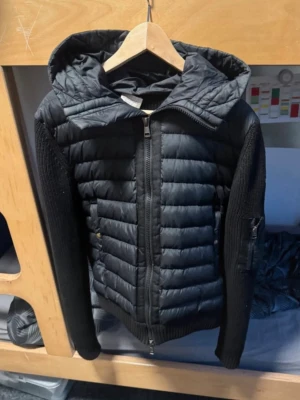 (Äkta) Moncler cardigan Jacka navyblue - Snygg svart pufferjacka med quiltad framsida och huva. Ärmarna är stickade vilket ger en cool kontrast till det vadderade tyget. Jackan har dragkedja framtill och fickor på sidorna samt en ärmficka. Perfekt för kalla vinterdagar. Navy blue stilren NYTT PRIS 3500kr MITT PRIS ENDAST 1760kr då jag vill köra endast SNABBAFFÄR 10/10🔥.